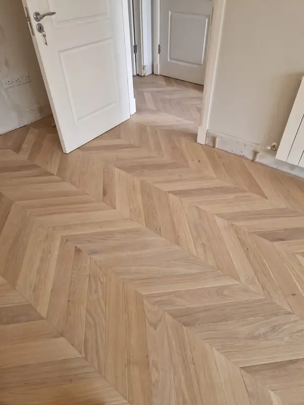 Light oak herringbone floor laid through a hallway and doorway
