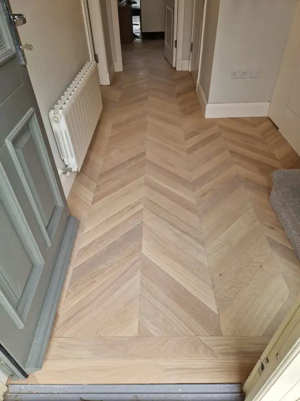 Herringbone oak hallway floor fitted neatly around a radiator and skirting