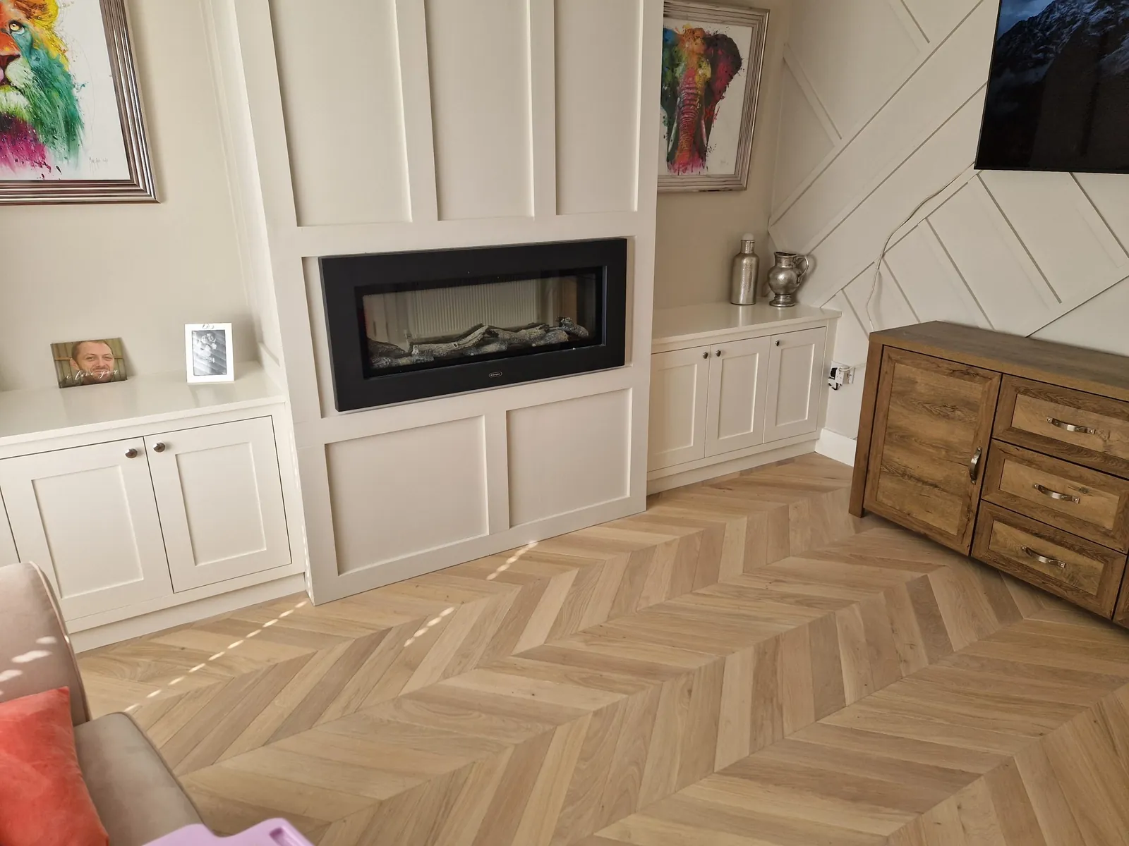 Herringbone oak flooring in a panelled living room with a modern fireplace