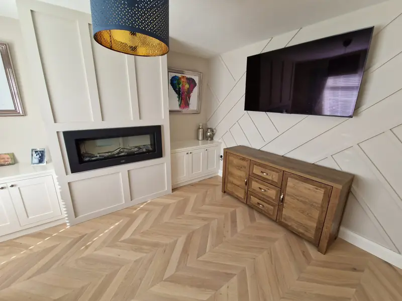 Herringbone living room floor with bespoke fitted media wall and cabinetry