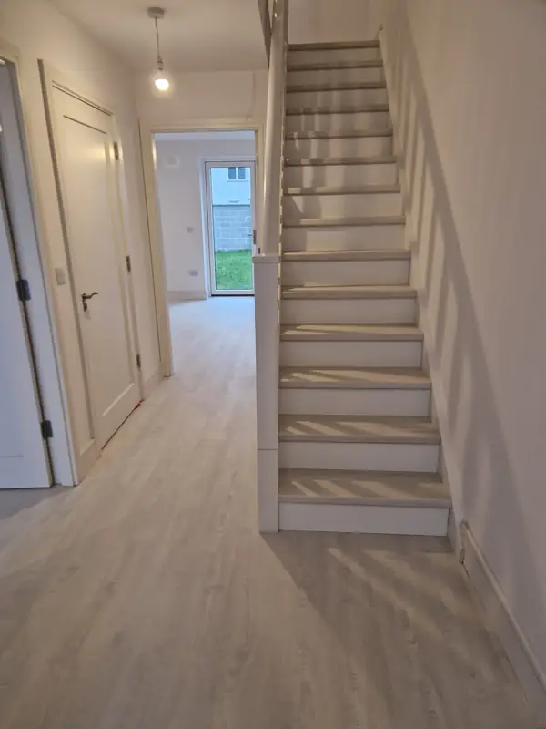 Plank flooring through a hallway with a matching renovated staircase