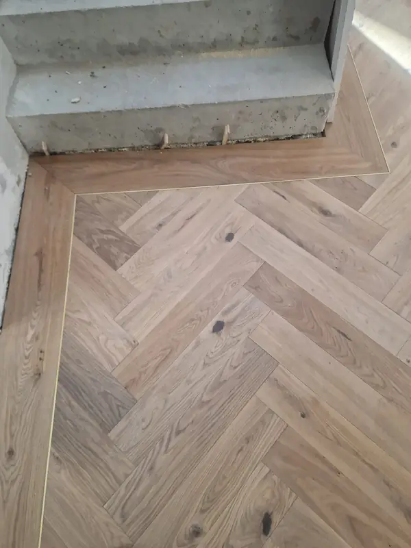 Herringbone flooring part-laid, showing subfloor preparation at a doorway