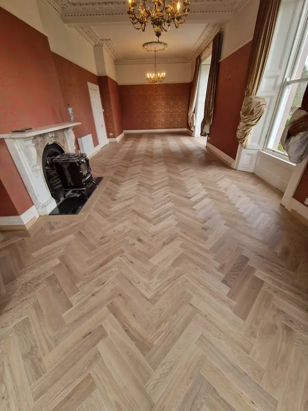 Herringbone parquet in a period room with marble fireplace and chandelier
