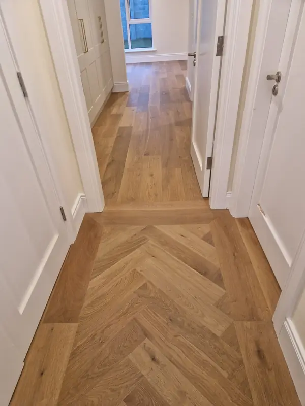 Warm oak herringbone floor running the length of a hallway