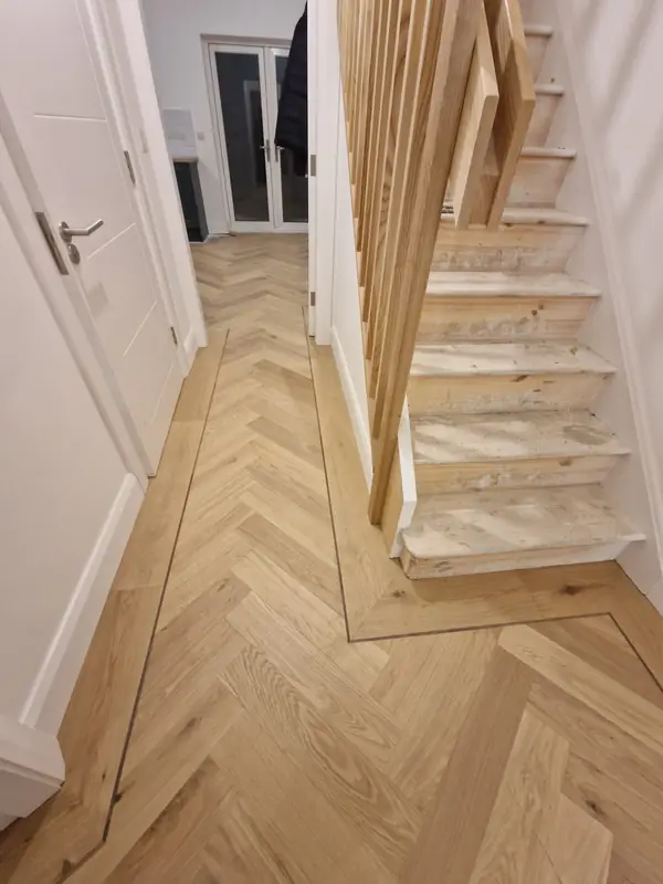 Herringbone hall floor beneath a modern oak balustrade staircase