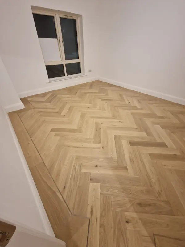 Pale oak herringbone flooring in a bright, freshly decorated room