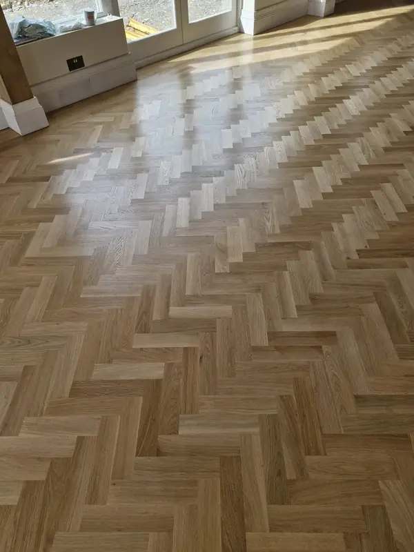 Freshly sanded and sealed herringbone floor catching afternoon light